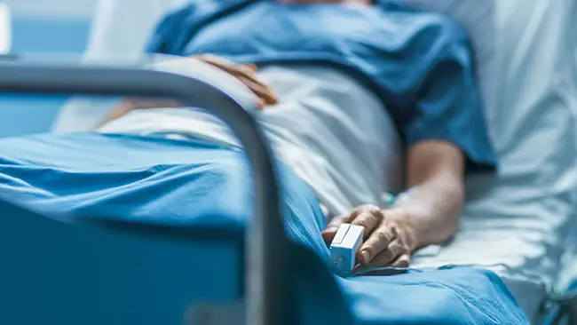 Ill man lies in hospital bed being monitored