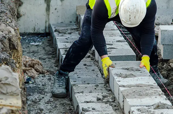 A construction worker lays a brick