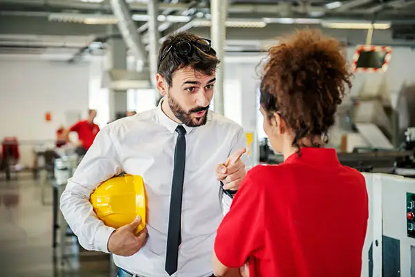 A male manager points fingers threateningly at female employee