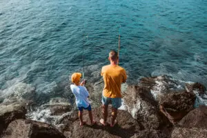 Father and son fishing together on rocks