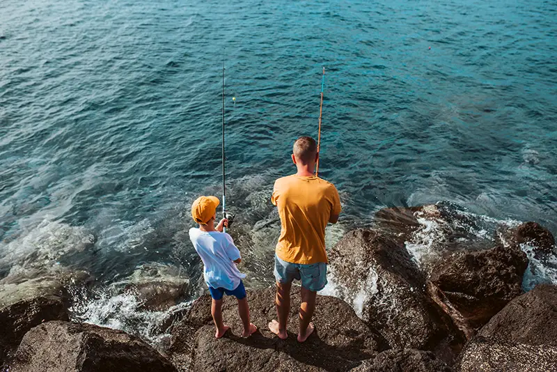 Father and son fishing together on rocks