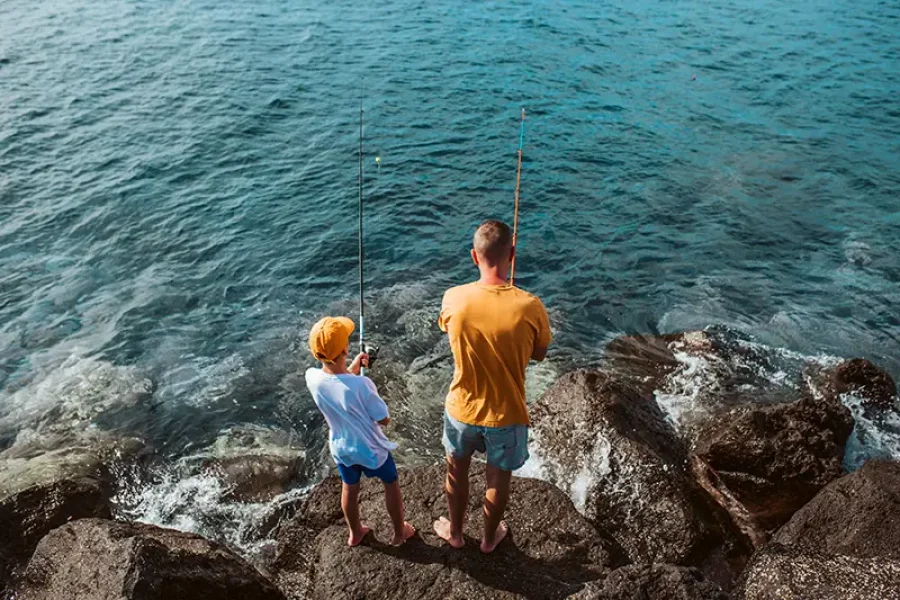 Father and son fishing together on rocks